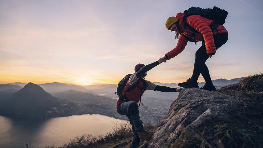 person helping another person up on a mountain