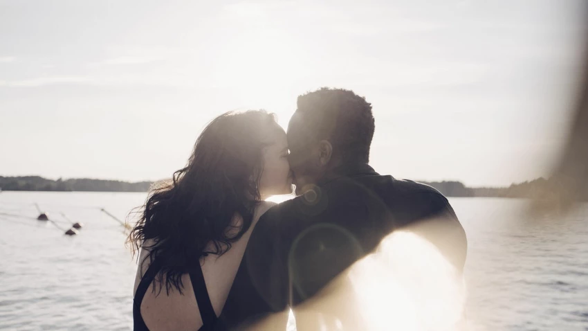 couple-kissing-while-sitting-against-lake