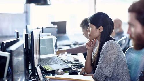 Woman thinking and looking at her computer screen in her office