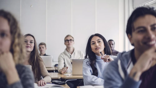 Male and female students sitting at desk in classroom