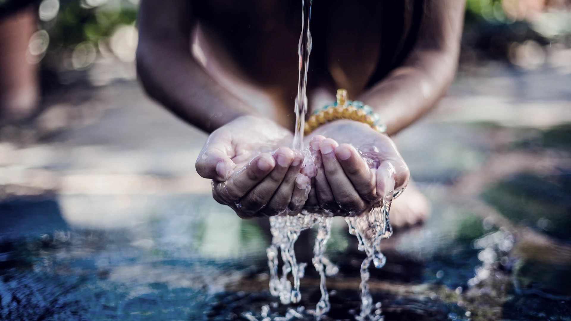Child drinking water with hands